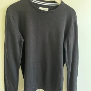 Svart stickad tröja från Pier One XS - En stilren svart stickad tröja från Pier One i storlek XS. Tröjan har rund halsringning, ribbade muddar och är långärmad. Gjord i mjuk bomull för skön känsla.