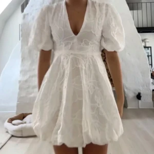 Vit kortklänning med puffärm från Zara - Superfin vit kortklänning från Zara med puffärmar och v-ringning. Klänningen har broderade blommor och en lätt volang nertill. Perfekt för sommarens alla tillfällen!