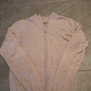 Beige stenströms tröja - Säljer en beige zip tröja i 100% merino ull från stenströms, riktigt snygg och funkar utmärkt i varmare väder. Ny pris ca 2300. Hör av dig vid funderingar! Storlek S men funkar även för M