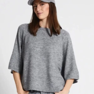 Grå stickad tröja med vida ärmar - Säljer en grå stickad tröja med rund hals och vida, trekvartsärmar. Tröjan har en avslappnad passform och är perfekt för lager-på-lager. Enkel och stilren design som passar till mycket.