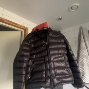 Svart äkta dunjacka från Moncler - Säljer en svart dunjacka från Moncler med klassisk quiltad design och dragkedja framtill. Jackan har lång ärm och två fickor med dragkedja. Dragkedjan är lite svår att dra igen men går nog lätt att laga.Allt annat är bra skick.köpt från vongreven closet så den är begagnad där av priset.storlek 3
