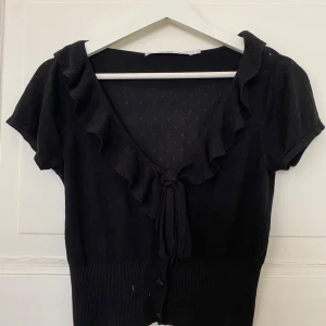 Svart topp med volang från Paris Kate & I - Garderobsrensning pågår! 👗 Shoppa loss bland en massa fina plagg. Kika in på min sida, så kanske du hittar något mer du gillar!  Har du frågor om ett plagg? Tveka inte att höra av dig!  (OBS: Kan tyvärr inte ta bilder med plaggen på.)