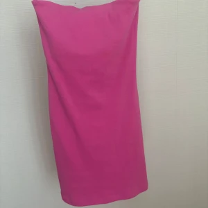 Rosa axelbandslös klänning - Säljer en snygg rosa axelbandslös klänning. Klänningen har en rak passform och är tillverkad i ett mjukt, stretchigt material. Perfekt för sommarens alla tillfällen!