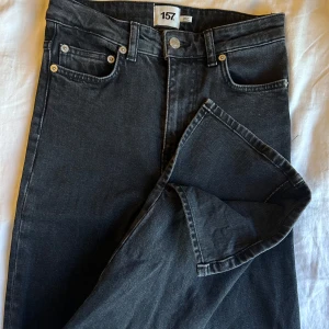 Svarta raka jeans från 157 - Säljer ett par svarta jeans från 157 med klassisk femficksdesign och raka ben. Jeansen har normal passform och är tillverkade i ett mjukt denimtyg. Perfekta för en stilren och enkel look.