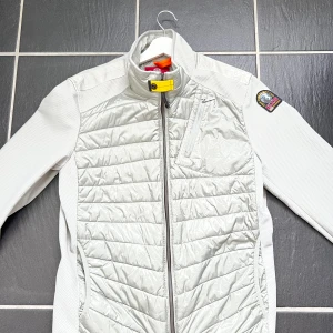 Ljusgrå hybridjacka från Parajumpers - Säljer en helt ny  ljusgrå Parajumpers Warm Up-jacka i storlek M. Snygg design med silver och detaljerna. Nypris 4500kr storlek M men passar L 