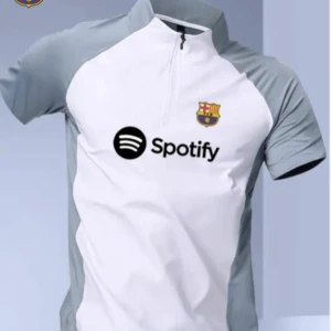 FC Barcelona vit och grå fotbollströja med halv dragkedja - Säljer en vit och grå fotbollströja från FC Barcelona med klubbmärke och Spotify-logga på bröstet. Tröjan har halv dragkedja vid halsen och korta ärmar. Perfekt för träning eller match!