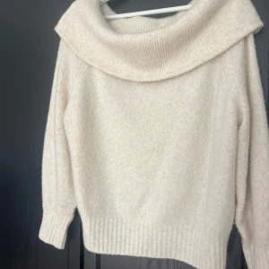 Vit stickad tröja med stor krage - Mysig begie stickad tröja med bred, nedvikt krage. Tröjan har lång ärm och ribbade muddar vid ärmslut och nederkant. Perfekt för kyliga dagar och enkel att matcha med olika outfits.