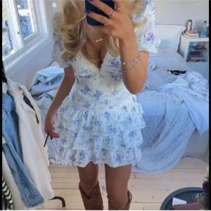 Vit och blå blommig sommarklänning - Supersöt kortklänning i vitt med blå blommigt mönster, perfekt i sommar! Säljer då den tyvärr är för kort för mig. Den är i helt nytt skick med prislapp kvar. 💕