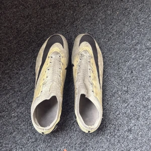 Nike mercurial varor 15 elite  - Säljer ett par Nike Mercurial fotbollsskor i grått med svarta detaljer och snörning. Skorna har plös och mönstrad ovandel i syntetmaterial samt fasta dobbar för spel på gräs. Andvänt i en säsong 