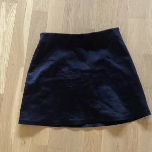 Svart kortkjol - Enkel svart kortkjol med rak passform. Kjolen är stilren och passar perfekt till många olika outfits. Materialet känns mjukt och lätt.