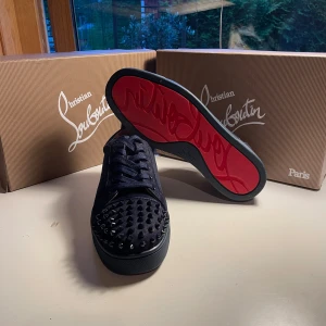  Christian Louboutin skor - Säljer ett par svarta sneakers från Christian Louboutin med ikonisk röd sula och coola silverfärgade nitar på tån. Skorna är i nytt skick men ända felet är att 7 spikar saknas men de syns sisådär vid användning 