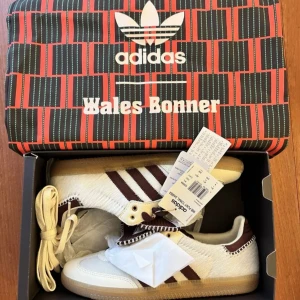 Adidas Samba Wales Bonner sneakers - Unika Adidas Samba Wales Bonner sneakers i vitt och brunt med klassiska ränder. Skorna har ovandel i skinn och päls, bruna detaljer och kontrastsömmar. Gummisula och extra skosnören medföljer. Perfekt för dig som gillar limited edition-samarbeten.