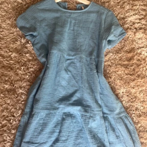 Blå kortärmad klänning från Only - Säljer en blå klänning från Only i storlek 152. Klänningen har korta ärmar, rund halsringning med liten v-ringning bak och ett lätt rynkat kjolparti. Materialet är mjukt och har en lätt struktur. Perfekt för varma dagar! Använd 1 gång🤍