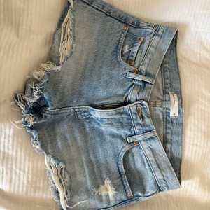 Ljusblå jeansshorts  - Skitsnygga lågmidjade jeansshorts i ljusblå! Slitna detaljer. I storlek 32