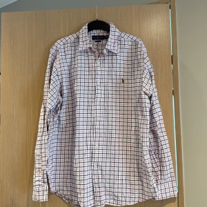 Rutig skjorta från Ralph Lauren - Säljer en klassisk långärmad skjorta från Ralph Lauren i vitt med blå och rosa rutor. Storleken är XL och skicket är bra om ni stryker den kommer den se som ny ut🤩 Nypris cirka 1600kr 