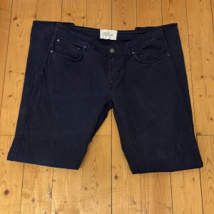 Mörkblå byxor från Oscar Jacobson - Säljer ett par mörkblå byxor från Oscar Jacobson med klassisk femficksdesign och knappgylf. Byxorna har raka ben och är tillverkade i ett mjukt bomullsmaterial. Perfekta för en stilren och avslappnad look.