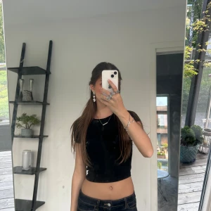 Svart croppad t-shirt - En enkel och stilren svart tajt croppad t-shirt från Gina. Rund halsringning och korta ärmar. Säljer då den tyvärr blivit för liten för mig. Passar skitbra till alla möjliga tillfällen