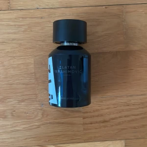 Zlatan Ibrahimovic Parfym - En stilren parfymflaska i svart glas med rund form och svart kork. Märkt med Zlatan Ibrahimovic på framsidan. Perfekt för dig som gillar eleganta och moderna dofter.