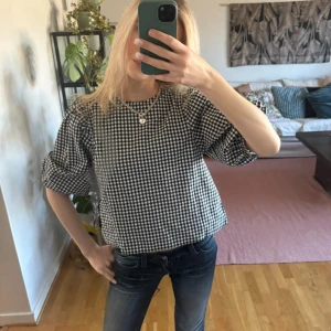 Rutig blus - Sååå söt rutig blus, på bilderna har jag den ”bak och fram” egentligen ska rosetterna på bild 3 vara framåt men jag brukar ha baksidan framåt vilket är så fint!🎀 Sparsamt använd och så fin, kommer tyvärr inte till användning längre❣️ Köpt för 400kr Postar samma som vid köp innan kl 20:40