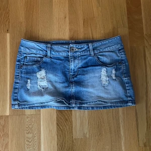 Blå jeanskjol från ONLY - Säljer en blå jeanskjol från ONLY med slitna detaljer framtill och klassiska fickor både fram och bak. Kjolen är kort och har en knapp och dragkedja i midjan. Perfekt för dig som gillar en avslappnad och trendig stil. Storlek 30 men skulle säga att den passar s-m💕💕midjemåttet är 42 cm och längden är 29cm