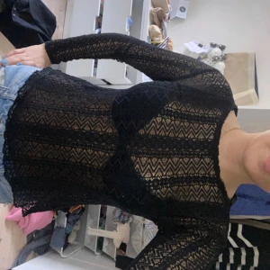 Svart spetsblus med lång ärm - Säljer en svart, transparent spetsblus med lång ärm och mönstrad spets. Blusen har ett snyggt zigzag-mönster och är perfekt att styla med jeans eller kjol.