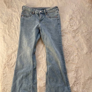 Ljusblå bootcut jeans  - Säljer ett par ljusblå bootcut jeans från H&M Divided i storlek 36. De är lite melerade i färgen och har sprättat upp de i benen vilket blev en snygg detalj. Använd ett fåtal gånger💕