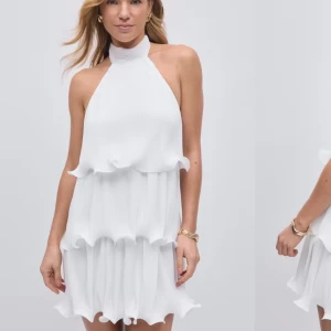 Vit volangklänning med halterneck  - Säljer en vit klänning från Gina Tricot med halterneck och knyt i nacken. Den är helt slutsåld på hemsidan och perfekt till studenten. Lappen är kvar och den är aldrig använd!