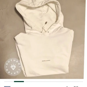 Vit hoodie från Saint Laurent - Supersnygg vit huvtröja med diskret logotyp framtill. Modell Rive Gauche. Inte gulnad, märken eller fläckar. Äkthetsintygad på Tradera. Skick 9/10. Längd ca 70 cm, bredd under arm ca 57 cm. Nypris dryga 8000 kr. 