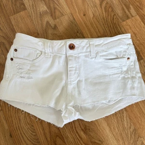 Vita jeansshorts med fransig kant - Snygga lågmidjade vita jeansshorts med rå, fransig kant och slitna detaljer framtill. Supersnygga!!!!💓💓💓För stora, därför jag säljer!