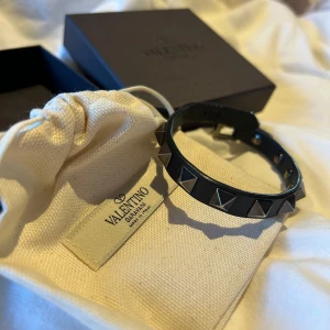 Svart armband med nitar från Valentino Garavani - Snyggt svart armband från Valentino Garavani med nitar i silver. Tillverkat i skinn och justerbart spänne. Köpt på NK i Sthlm.