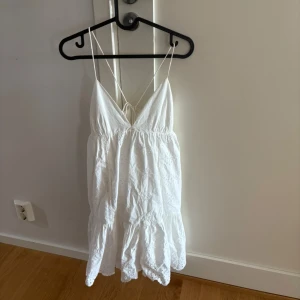 Vit sommarklänning med spetsdetaljer - Söt vit klänning med tunna axelband och v-ringning. Klänningen har spetsdetaljer och volang nertill med öppen rygg och knyt i ryggen. Superskön och perfekt nu till sommaren!☺️Storlekt M men passar mig som har S vanligtvis.