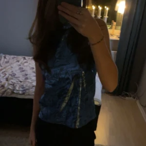 Blå glittrig halterneck-top - Säljer en jättefin blå glittrig halterneck-top med svart och silvermönster. Använd endast 1 gång så perfekt skick. Pris kan diskuteras! Storlek M men passar S då den är mindre i storleken