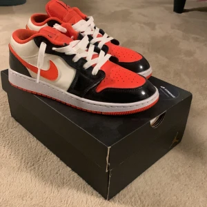 Nike Air Jordan 1 Low GS Halloween  - Säljer ett par Nike Air Jordan 1 Low SE i svart, vit och orange. Jag säljer dom för att dom är för små men hoppas att den kommer till användning för någon annan! Storlek 40 men passar även 41. Kan sänka priset vid snabb affär!