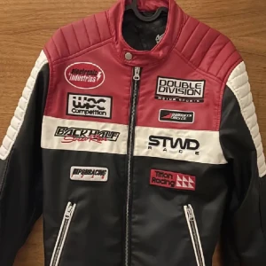 Bikerjacka - Säljer en snygg racingjacka i rött, svart och vitt med flera coola patches och dragkedjor. ❤️Använd 1 gång! Perfekt för dig som vill sticka ut med en sportig och edgy stil.