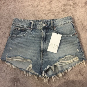 Blå jeansshorts med fransar från Zara - Säljer ett par blå jeansshorts från Zara med fransig kant och slitna detaljer framtill. Medelhög midja men ser även low wasited ut. Säljer för att dom är för stora för mig! Är helt oanvända köpte förra året men inte använt dom! Ny pris är ungefär 300-450 och säljer för 300! Pris kan diskuteras! (Ej retur)