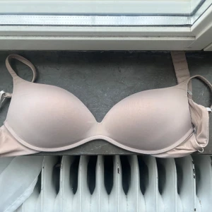 Intimissimi bh - Säljer en enkel och stilren beige bh med vadderade kupor och justerbara axelband. Säljer då jag trodde jag köpte en i push up men fick hem denna.  UTAN push up! Storleken i förra beskrivningen var 80C men jag skulle säga att den lutar mer emot 80D. Den har små rivningar och är nopprig här och där; därav det billiga priset. Går alltid att pruta. För mer bilder kom privat