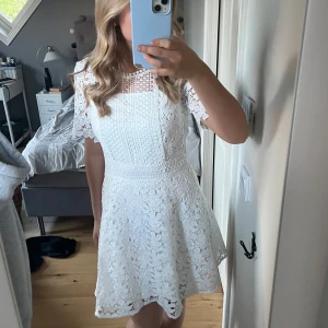 Vit spetsklänning från Bubbleroom - Superfin vit spetsklänning från Bubbleroom i storlek 36. Klänningen har korta ärmar, rund halsringning och dragkedja i ryggen. Blommigt spetsmönster och lätt utställd kjol. En perfekt klänning till sommaren. Klänning är bara använd en gång och ser oanvänd ut!🌸🌸🌸