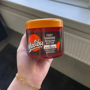 Malibu Fast Tanning Bronzing Butter - En burk med Malibu Fast Tanning Bronzing Butter, en brun- och orangefärgad kräm med beta-karoten för snabbare solbränna. Självklart oanvänd, visas på bild 2.