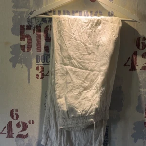 Vita linnebyxor från East West - Säljer ett par vita linnebyxor från East West med resår och dragsko i midjan. Byxorna är lätta och luftiga, perfekta för varma dagar. Klassisk rak passform och enkel stil som funkar till mycket.