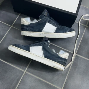 Valentino flycrew STEAL ‼️‼️‼️‼️ - Säljer ett par svarta sneakers från Valentino flycrews  med vita detaljer och vit sula. Skorna har klassisk snörning och en stilren design med tydlig logotyp på sulan. Perfekta för dig som gillar exklusiva och snygga sneakers.