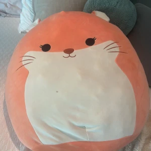 Stor Squishmallows hamster gosedjur - Supermjuk och stor Squishmallow i form av en hamster med orange och vit päls, söta broderade ögon och morrhår. Har små öron, svans och rund form. Perfekt som kramdjur eller mysig inredningsdetalj. Orginal pris 850kr. Pris kan diskuteras!