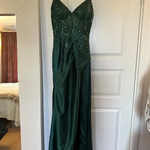 Grön långklänning med paljetter -   Säljer en fantastisk balklänning – endast använd en gång! Elegant design med justerbar rygg för perfekt passform. Perfekt för bal, bröllop eller annan finare tillställning.strolek xs-m   