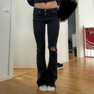 Svarta bootcut low jeans med slitningar - Snygga svarta bootcut jeans med slitningar på knäna. Perfekta för en avslappnad stil. Storleken är S/33 och jag är 1,66!!