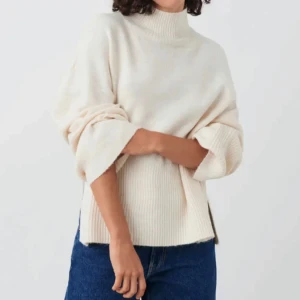 Beige stickad polotröja - Säljer en mysig beige stickad polotröja med ribbade detaljer. Tröjan har en avslappnad passform och långa ärmar, perfekt för kyligare dagar. Den höga kragen ger extra värme och stil. Passar utmärkt till jeans eller kjol för en avslappnad look.