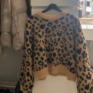 Leopardmönstrad stickad tröja från Vero Moda -  leopardmönstrad stickad tröja från Vero Moda. Tröjan har en beige och svart färgkombination med ribbade kanter vid hals, ärmslut och nederkant. Använd max 2 gånger 