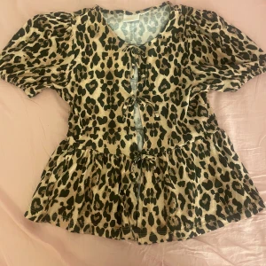 Leopardmönstrad topp från Gina Tricot - Säljer en leopardmönstrad topp från Gina Tricot med korta ärmar och knytning framtill. Lite tajtare vid armens ände. Sitter jättefint på.