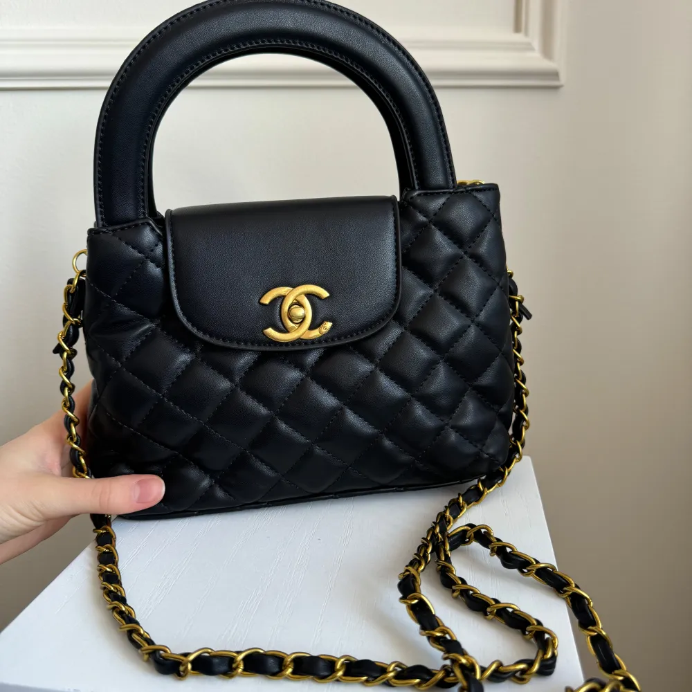 Elegant svart quiltad handväska med gulddetaljer och kedja. Väskan har ett klassiskt märke på framsidan och en praktisk handrem. Perfekt för att ge en lyxig touch till din outfit. Väskan är ny och oanvänd! !! Inte köpt från zara !! Skriv till mig för flera bilder . Laukut & Käsilaukut.
