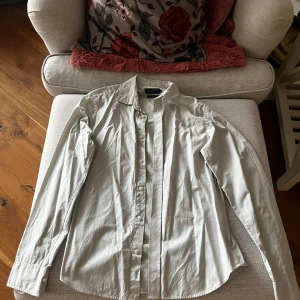 Grön skjorta från Riley - Säljer en stilren grön skjorta från Riley i storlek S. Skjortan har en slim fit passform och är tillverkad i ett mjukt bomullsmaterial. Den har långa ärmar och knappar framtill. Perfekt för en elegant look.