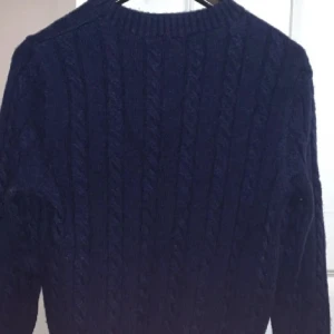 Mörkblå stickad tröja från Ralph Lauren - Säljer en snygg mörkblå stickad tröja från Ralph Lauren med kabelstickat mönster. Köpt för 2300 för nån månad sen men passar mig inte längre. Perfekt för kyligare dagar! Pris kan diskuteras 