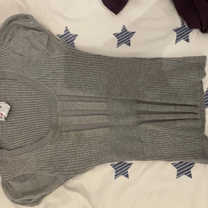 Grå ribbad topp från Pout - Säljer en stilren grå ribbad topp från Pout. Toppen har korta ärmar och en rund halsringning, perfekt för en avslappnad look. Den är tillverkad i ett mjukt material som ger en bekväm passform. Passar utmärkt till både jeans och kjol.